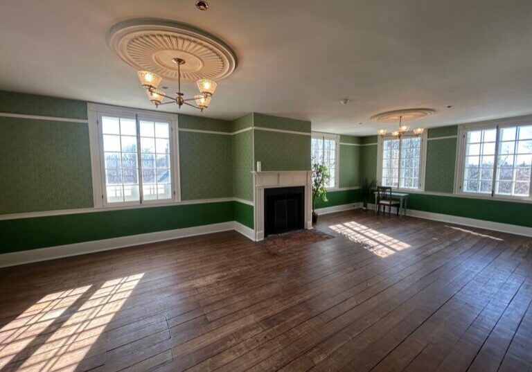 Wide angle photo of Billings Estate Museum. Including green ornate wallpaper, brown refinished flooring, period correct lighting fixtures with ornate WoodSource made medallions.
